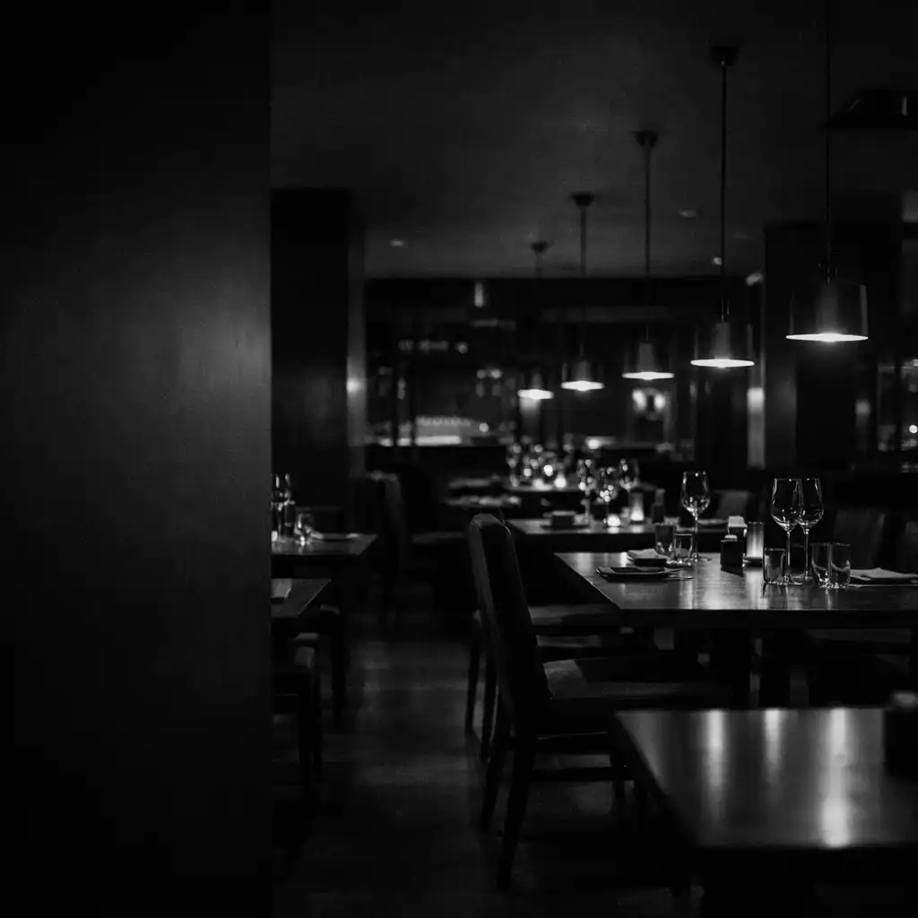 Večerní interiér Savory Dining Room s tmavými stoly a nízkým světlem