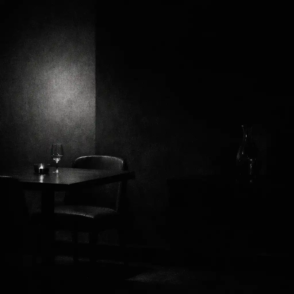 Tichý večerní kout Savory Dining Room s tmavým stolem a jediným zdrojem světla
